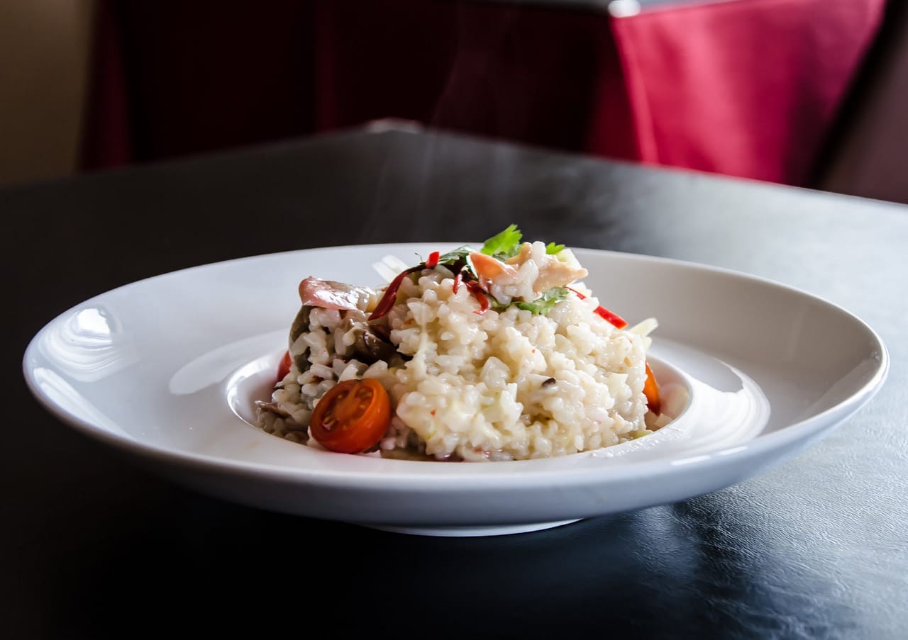Plato hondo de arroz meloso con tomate cherry y hierbas frescas