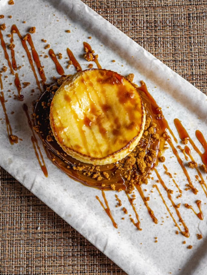 Tarta de queso con caramelo y galleta desmenuzada en bandeja blanca