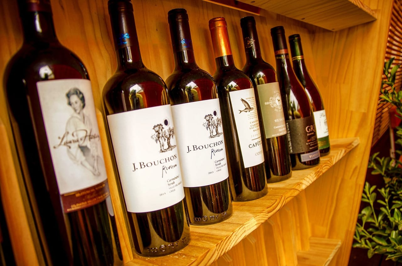 Botellas de vino tinto alineadas en un estante de madera